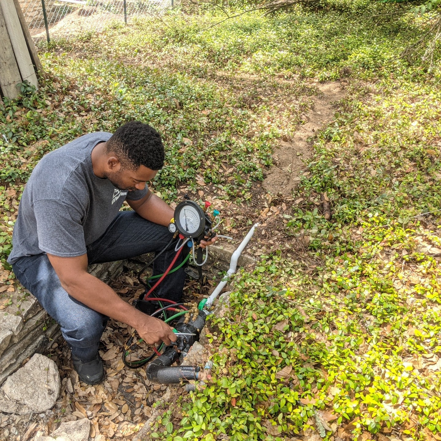 Technician performing residential backflow test with gauges