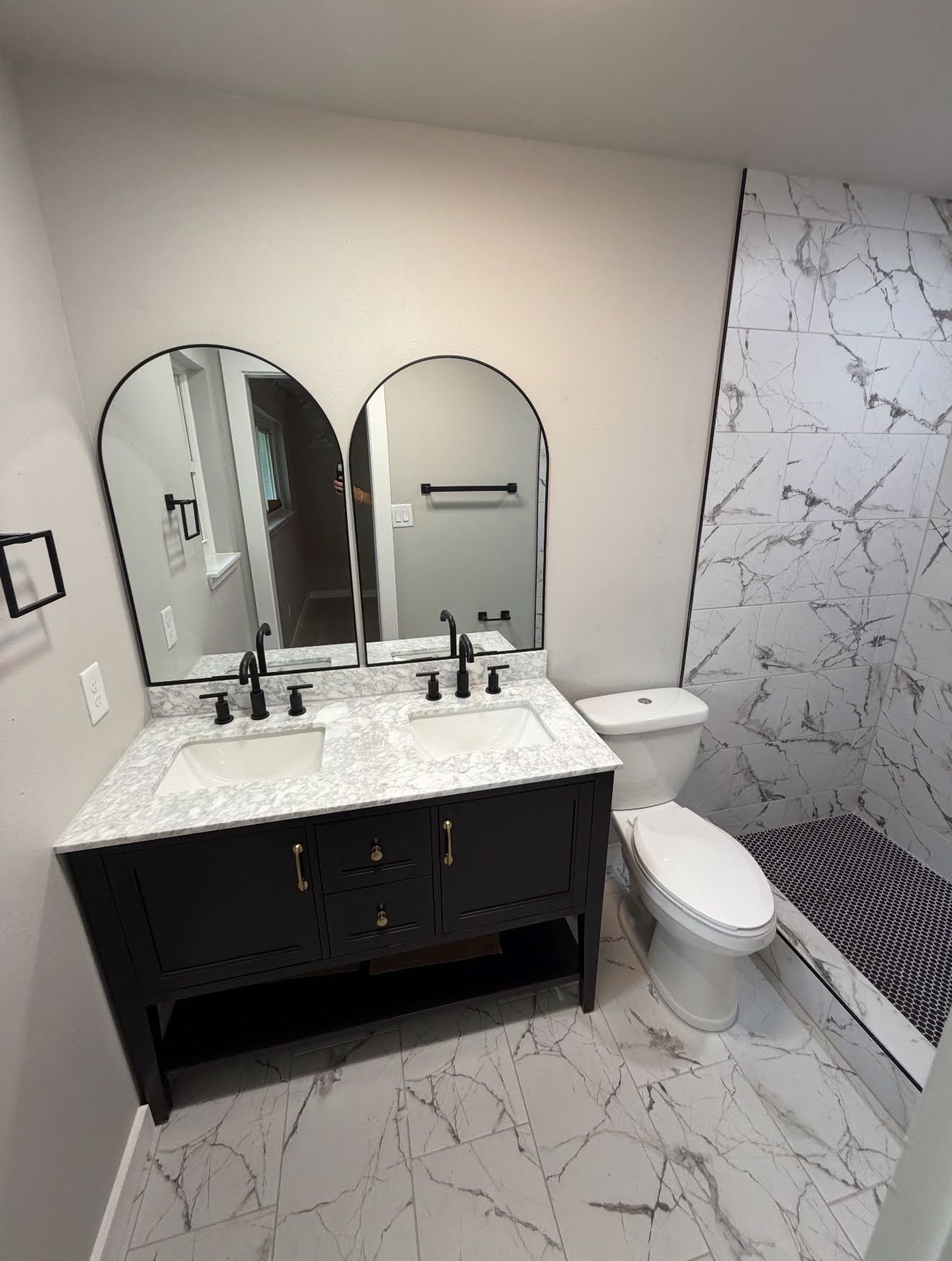 Bathroom remodel with marble shower, dual-sink vanity, and arched mirrors