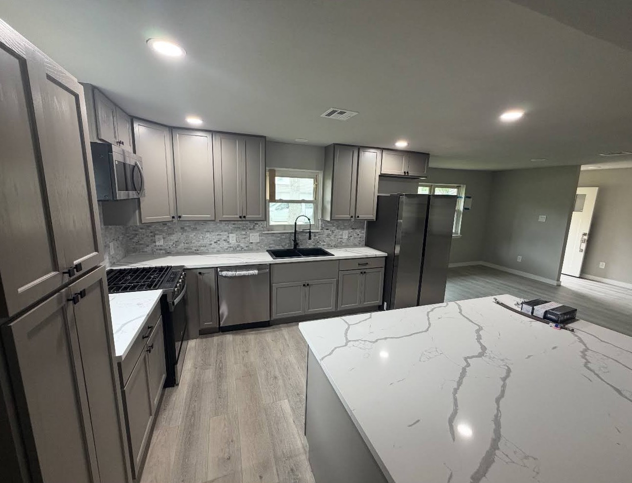 Full kitchen remodel with custom gray cabinets, waterfall island, and stainless appliances